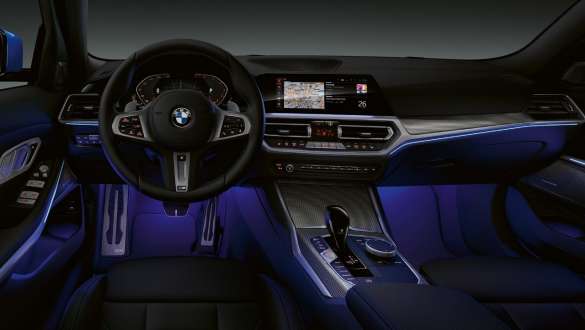 BMW 3 Series, Ambient light. Front view of the driver's cockpit of the BMW 3 Series with by Ambient light blue illuminated legroom.
