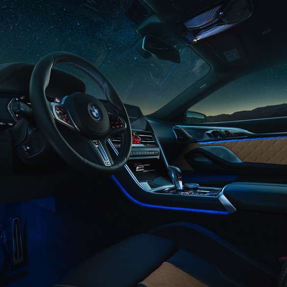 BMW M8 Coupé, cockpit. BMW M8 Coupé, cockpit at night with M leather steering wheel and blue ambient light.