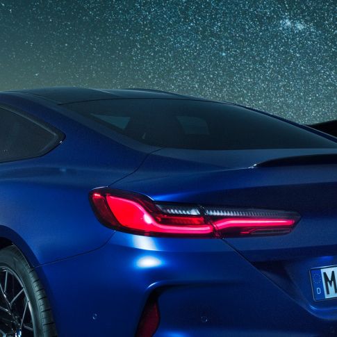 M rear spoiler BMW M8 Coupé in Marina Bay Blue metallic, nightly close-up of shoulder section with M rear spoiler in Carbon.