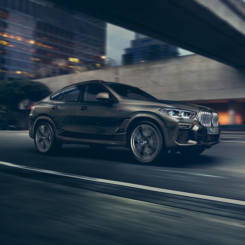 BMW X6 driving. BMW X6 in three-quarter front perspective driving in front of an urban setting.