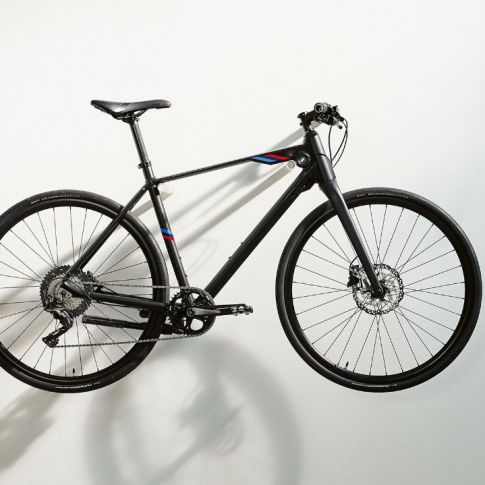 The picture shows a BMW M Bike Matt Black with BMW M Motorsport branding stripes hanging on a wall bracket. The picture shows a BMW M Bike Matt Black with BMW M Motorsport branding stripes hanging on a wall bracket.