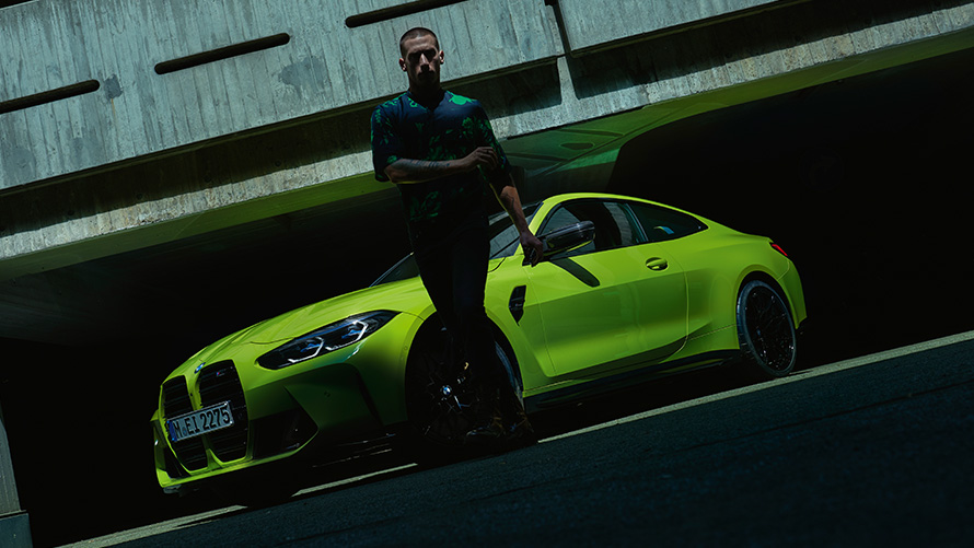 BMW M4 Competition Coupé with M xDrive three-quarter front view with model BMW M4 Competition Coupé with M xDrive Sao Paulo Yellow metallic three-quarter front view with model