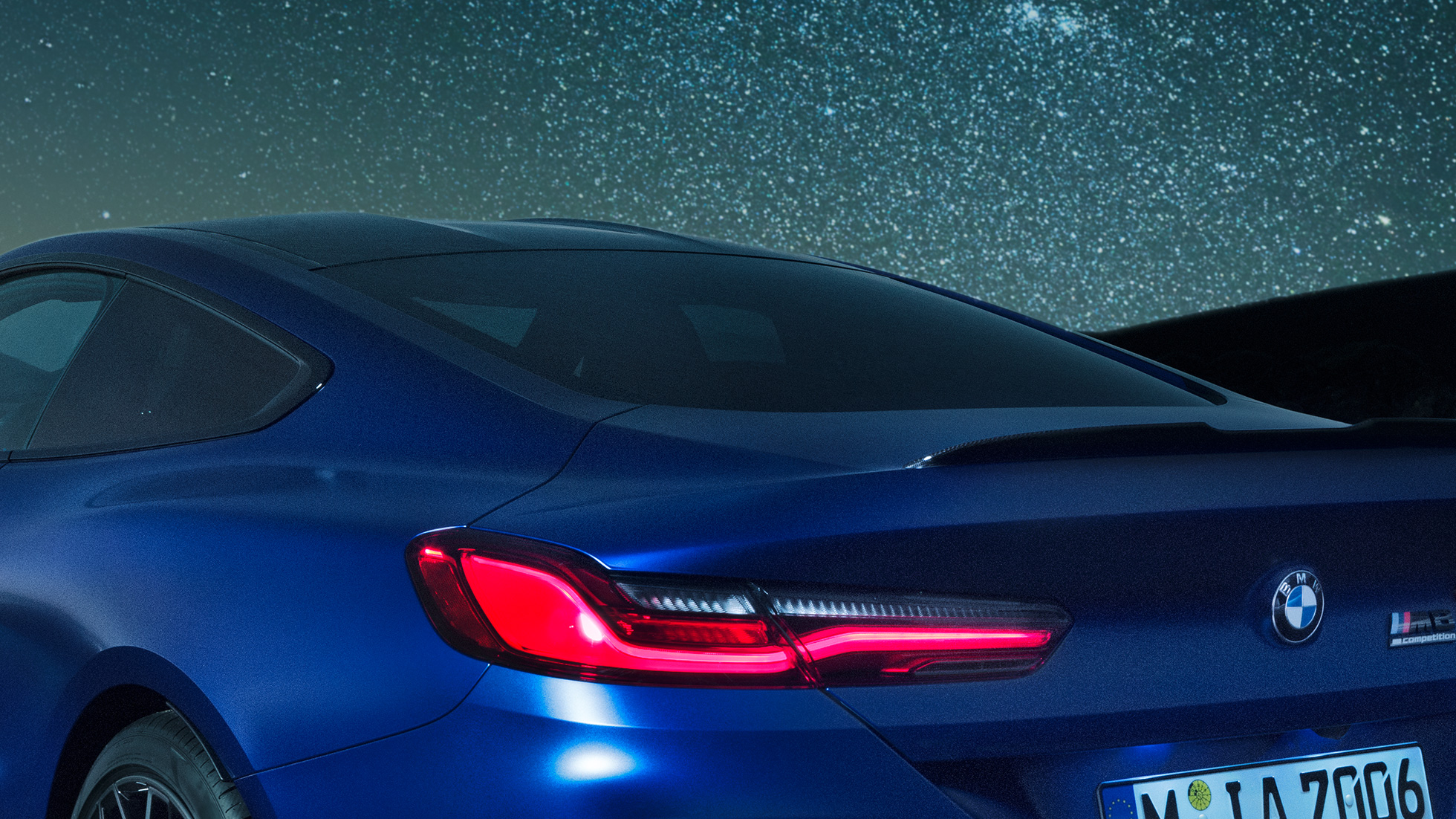 M rear spoiler BMW M8 Coupé in Marina Bay Blue metallic, nightly close-up of shoulder section with M rear spoiler in Carbon.