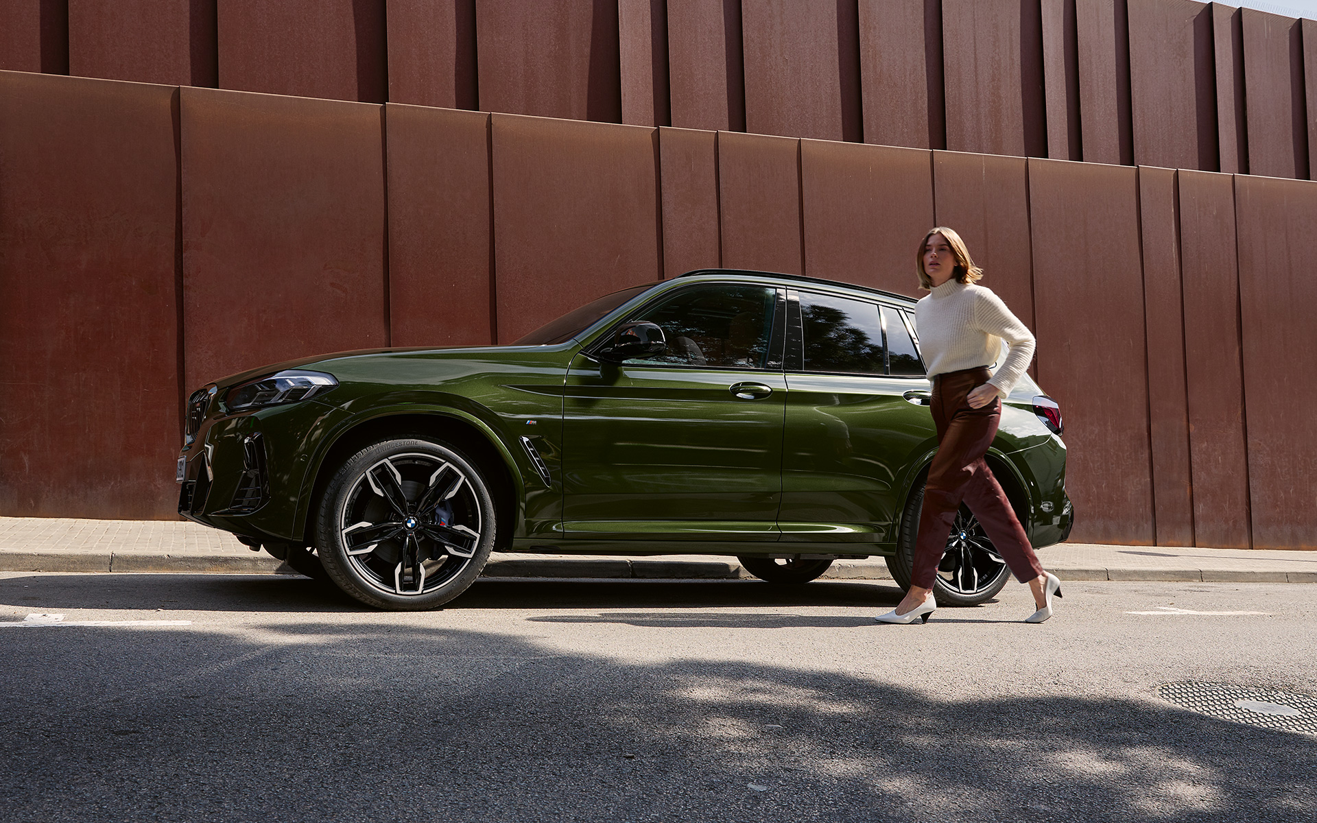 BMW X3 M40i G01 LCI Facelift Malachite Green metallic side view with female model BMW X3 M40i G01 LCI Facelift Malachite Green metallic side view with female model
