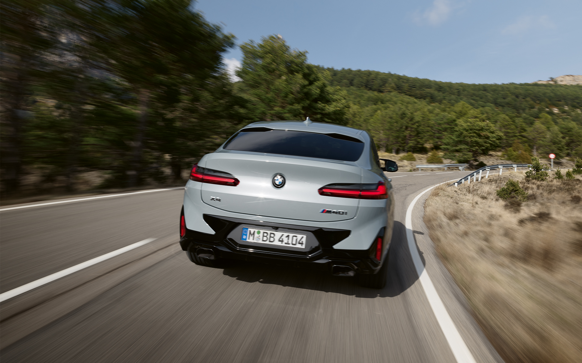 BMW X4 M40i G02 LCI 2021 Facelift three-quarter rear view in front of glass facade