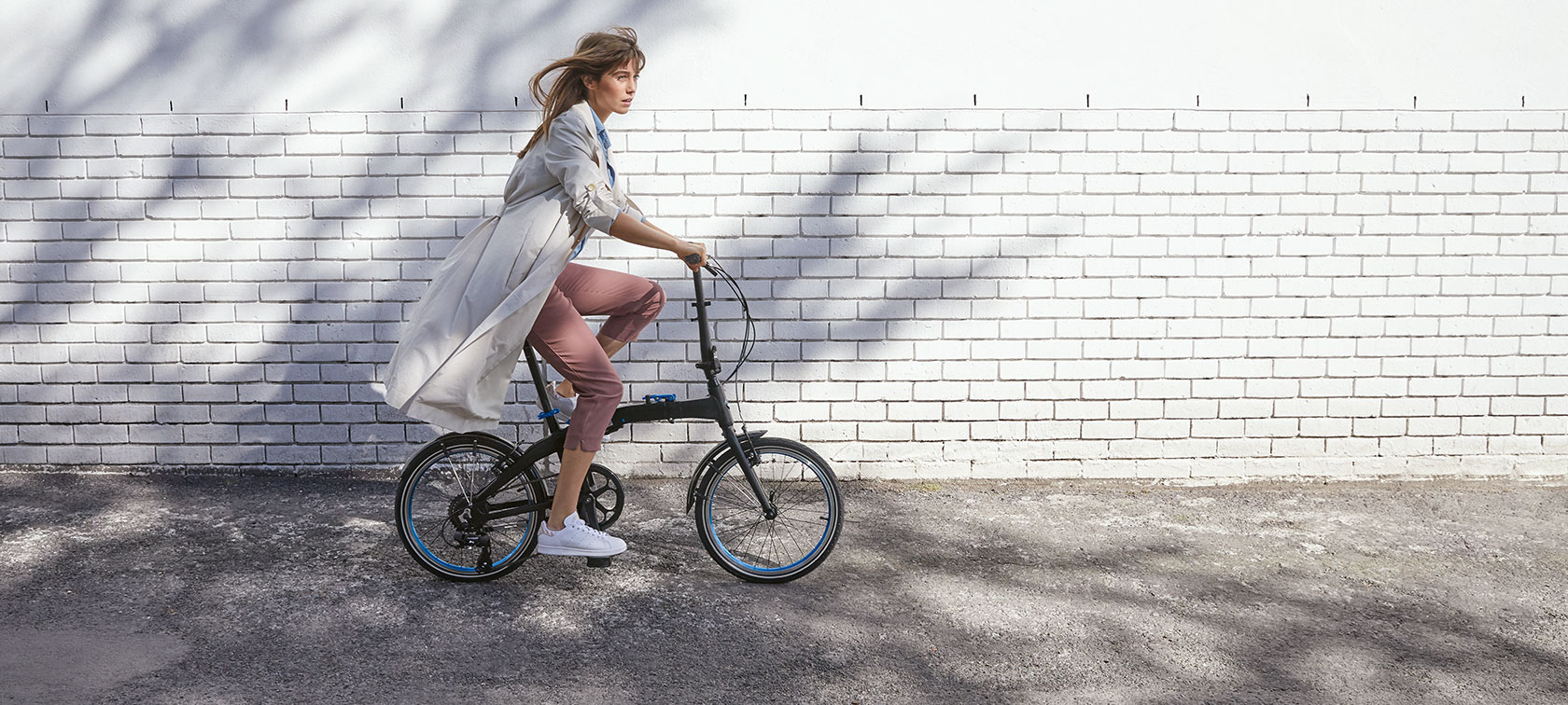 The picture shows a woman riding a BMW Folding Bike.