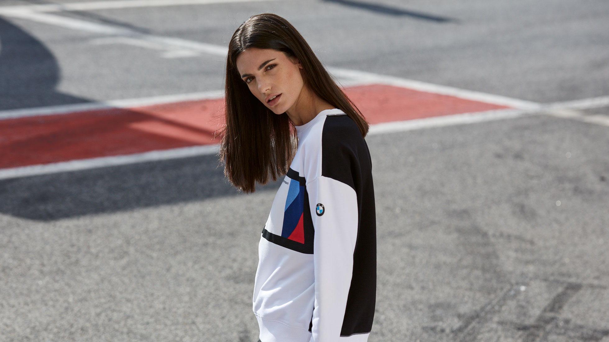 In the picture, a young woman is shown wearing a BMW M Motorsport Sweater for women. In the picture, a young woman is shown wearing a BMW M Motorsport Sweater for women.