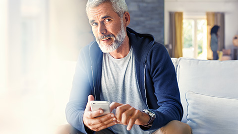 BMW ConnectedDrive Store Man with smartphone sitting on sofa
