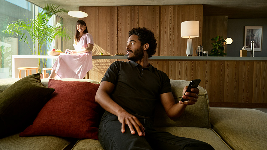 Share BMW Digital Key BMW Digital Key Share Man with smartphone in hand sitting on sofa with woman in background