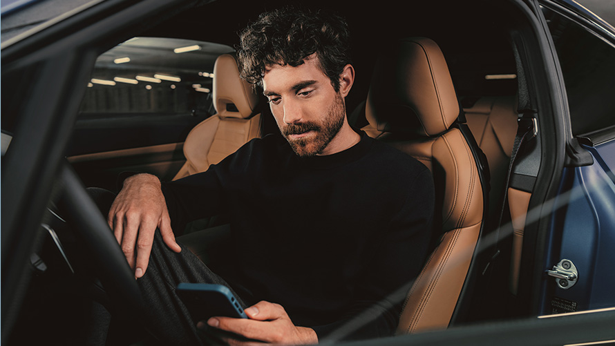 Man sitting in BMW Man sitting in BMW and looking at his smartphone