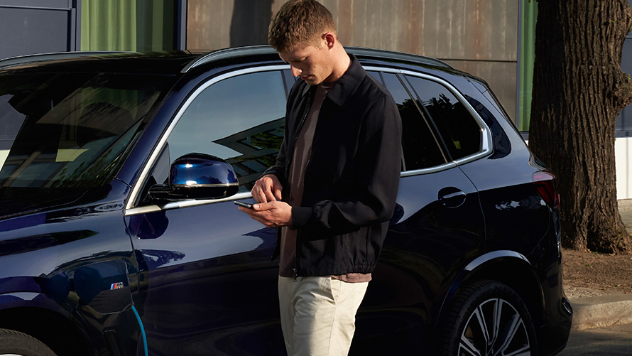 Remote Software Upgrade Man in front of BMW looks at his smartphone