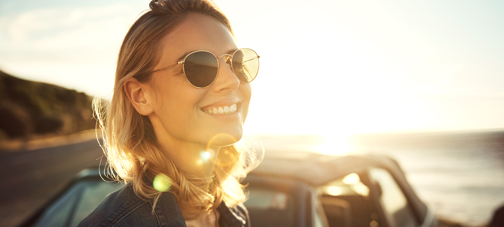Original BMW Accessories and parts Original BMW Accessories: woman wears sun glasses and smiles, BMW in the background