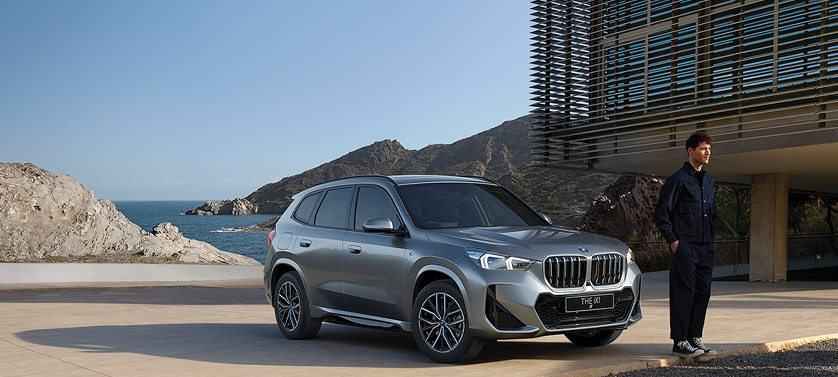 BMW iX1 U11 BEV 2022 Mineral White metallic three quarter front view serpentine mountain road driving