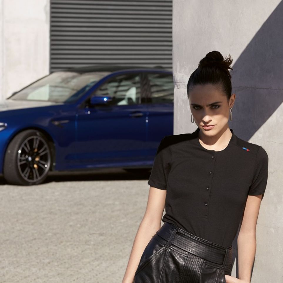 A car burns rubber around a male model with a bag from the BMW M Collection. A car burns rubber around a male model with a bag from the BMW M Collection.
